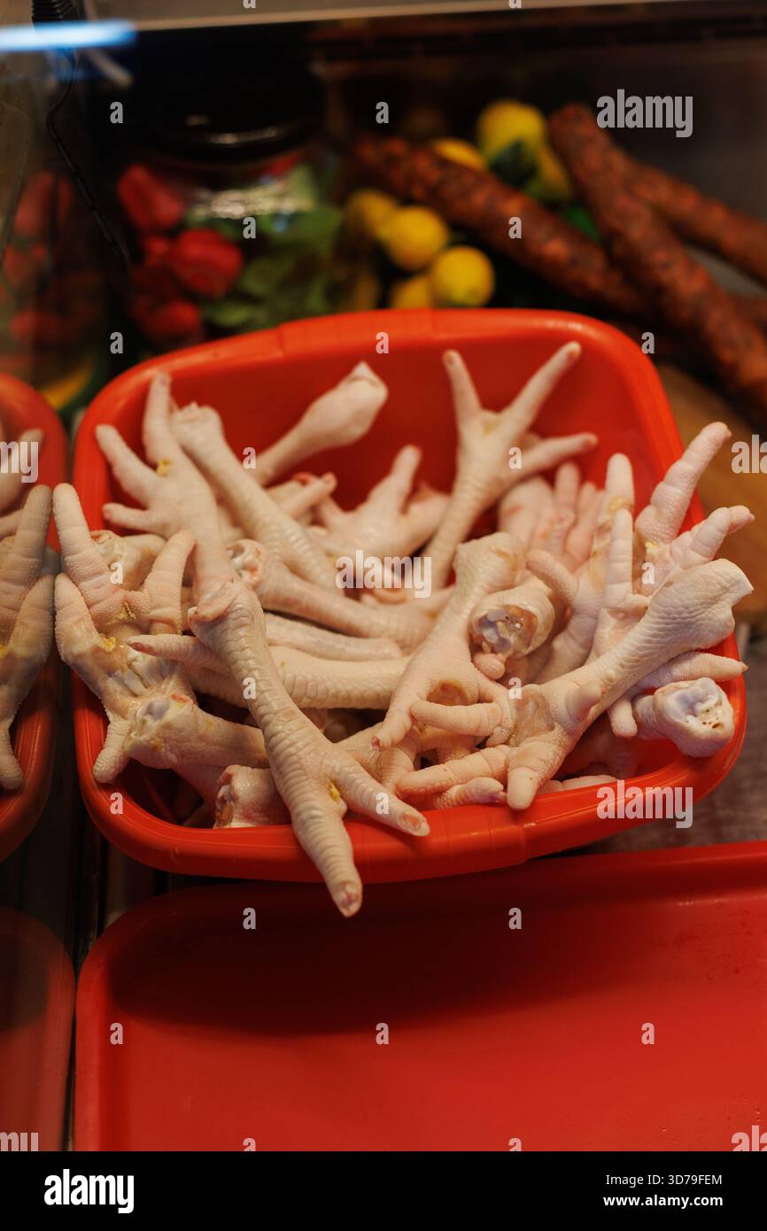 Pieds de poulet frais exposés dans un panier rouge sur un marché local Banque D'Images