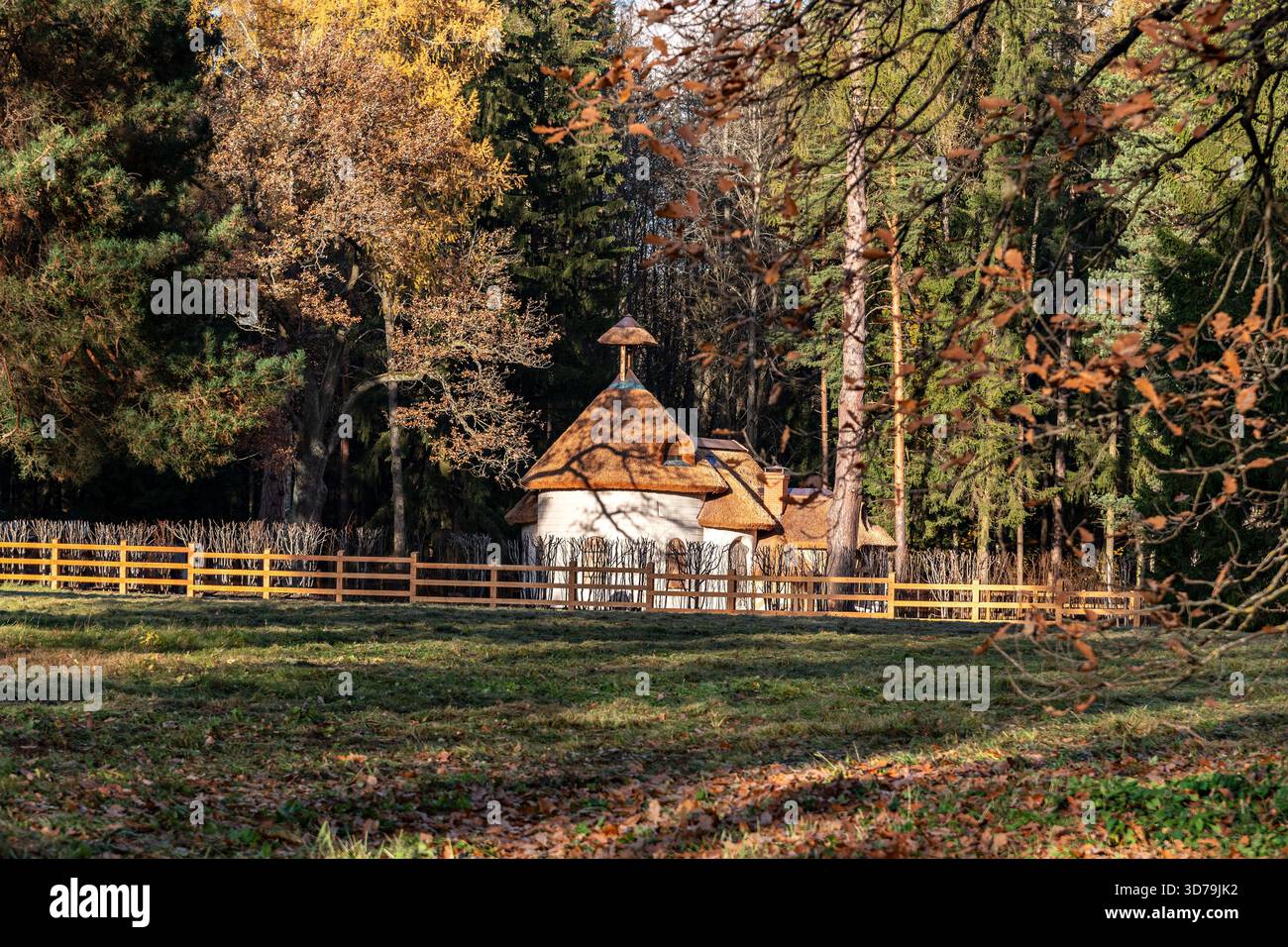 Old Chalet est une petite maison blanche avec un toit de chaume et une clôture en bois dans le parc municipal de Pavlovsk un jour d'automne ensoleillé. Banque D'Images