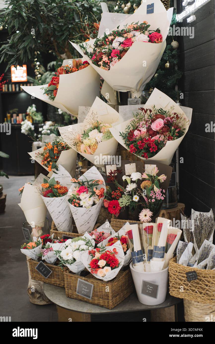 Bouquets de fleurs fraîches exposés dans une boutique de fleuriste, disposés dans du papier d'emballage blanc Banque D'Images