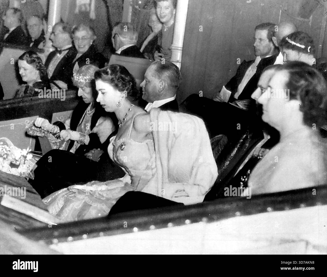 Et personne n'a aidé la reine avec son manteau -- la reine Elizabeth a enlevé son manteau de fourrure blanche elle-même dans la boîte royale au Royal Albert Hall de Londres mercredi soir quand elle a assisté à un concert-bénéfice pour les fonds de secours britanniques et néerlandais contre les inondations. La femme âgée à gauche est la princesse Marie Lousie, petite-fille de la reine Victoria. L'homme à droite d'Elizabeth est Dirk U. Stikker, ambassadeur néerlandais en Grande-Bretagne. À droite, dans le profil sont MRS Stikker et le Duc d'Édimbourg. 06 mars 1953. (Photo de AP Wirephoto). Banque D'Images