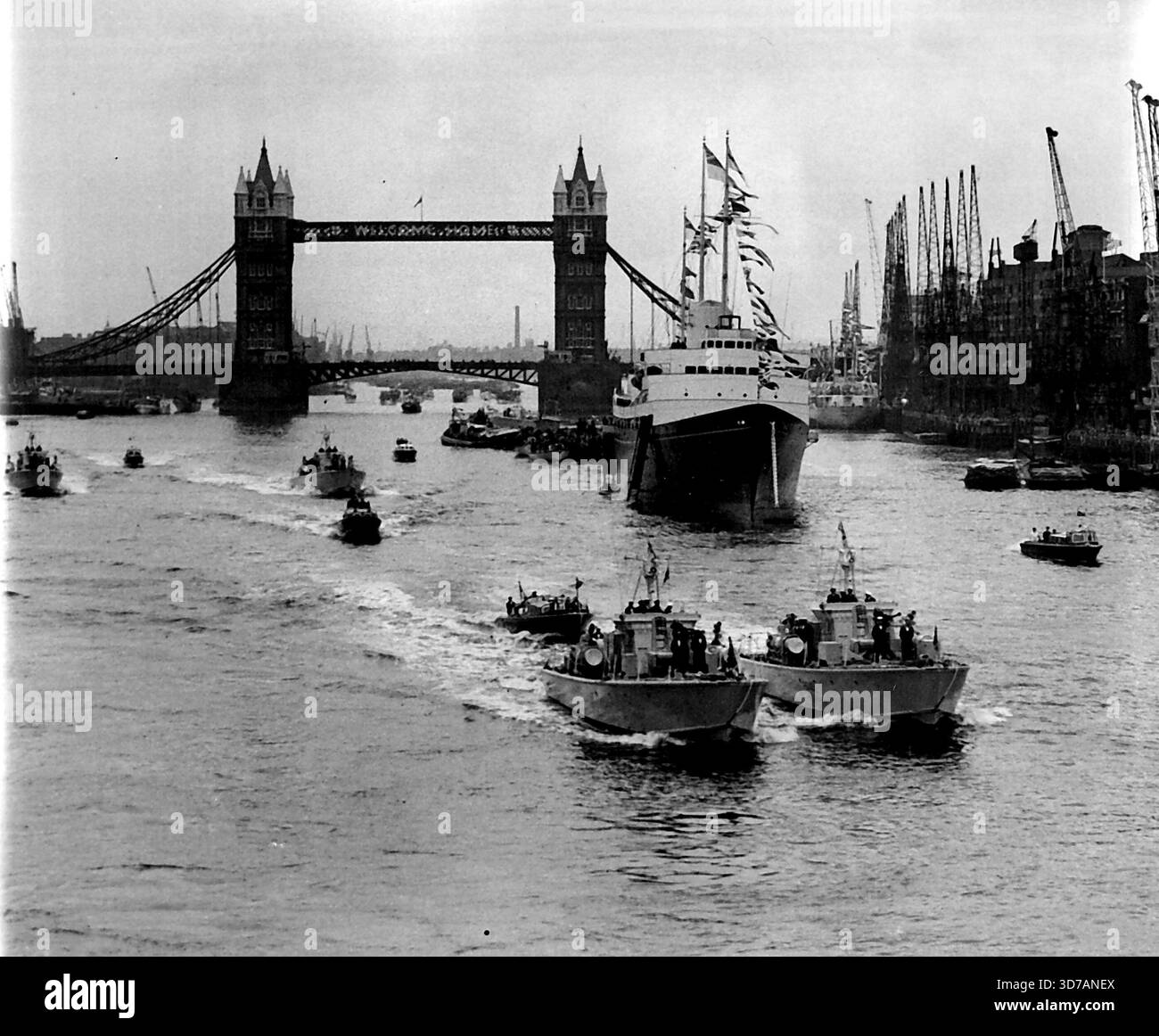 'Britannia' in the Pool - Queen and Duke are Home - des spectateurs sur des bateaux fluviaux surpeuplés applaudissent le yacht royal Britannia lorsqu'elle entre dans la piscine de Londres jusqu'à aujourd'hui (samedi), ramenant la Reine et le duc d'Édimbourg au cœur de la capitale après leur excursion de 50 000 kilomètres dans le Commonwealth. Le yacht royal avait traversé Tower Bridge (arrière-plan) sur le chemin de son berth, Battle Bridge Tier dans la piscine. 15 mai 1954. (Photo de Reuterphoto). Banque D'Images