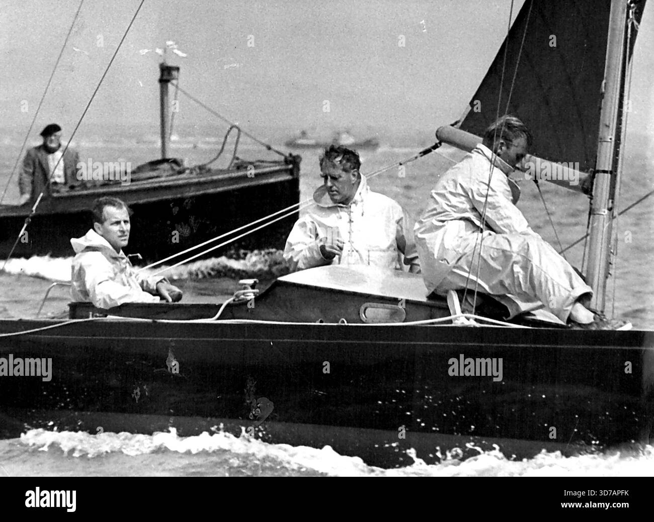 Sportif polyvalent le duc d'Édimbourg à la barre du yacht Bluebottle, en compétition dans une course à Cowes Regatta. Le Duke est un bon joueur de cricket et de polo. Lors d'une course sous le vent à une régate de Cowes, le Duke of Edinburgh dirige la classe Dragon Bluebottle qui a de bonnes chances de gagner le droit de représenter aux Jeux olympiques de Melbourne. Uffa Fox est le camarade qui se tient dans le cockpit. 25 août 1953. Banque D'Images