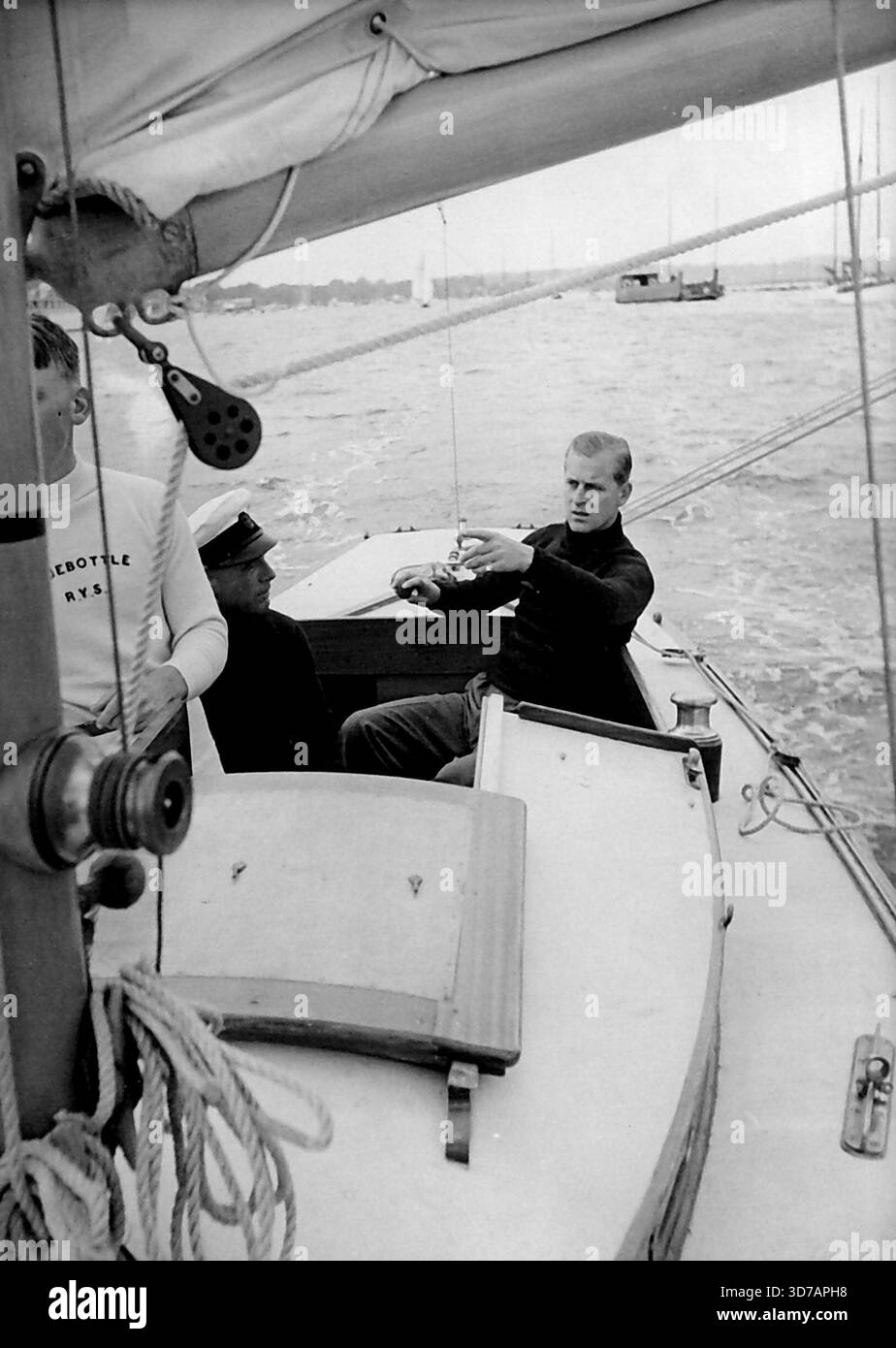 Le duc d'Édimbourg à bord du « Bluebottle » -- le « Bluebottle », un yacht de la classe Dragon (app.18 pieds de long) a été présenté à leurs Altesses Royales la princesse Elizabeth. Et le duc d'Édimbourg par le Club de voile de l'île. - Le duc a contesté sa première course sur le yacht quand il est entré dans le "Bluebottle" lors d'un récent événement de yachting à Cowes. Dans l'équipage de trois bateaux, le duc a agi comme troisième main. Le premier jour, 'Bluebottle' est arrivé troisième mais s'est disqualifié par le pâturage d'une bouée; le second, elle a fini 7th. La « Bluebottle » naviguant sur le Solent. Ensuite, le duc d'Édimbourg Banque D'Images