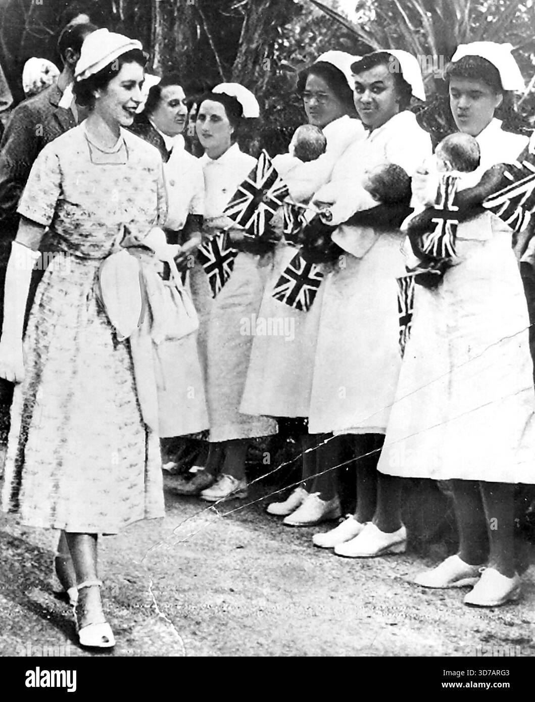 La reine voit les triplés du couronnement des Bermudes - la reine Elizabeth, à gauche, regarde les triplés Miller, Philips Mary, Margaret Rose et Elizabeth Anne, détenus par leurs infirmières lors de sa visite aujourd'hui à l'hôpital pour enfants sur l'île d'Irlande, qui est de l'autre côté du canal de Hamilton, aux Bermudes. Les triplés sont connus sous le nom de « triplet du couronnement », étant nés le 4 juin, la semaine du couronnement d'Elizabeth. La reine Elizabeth lors de sa visite aux Bermudes s'intéresse aux triplés Miller - Philipa Mary, Margaret Rose et Elizabeth Anne - détenus par leurs infirmières. Les triplés sont connus sous le nom de « triplés Coronation » Banque D'Images