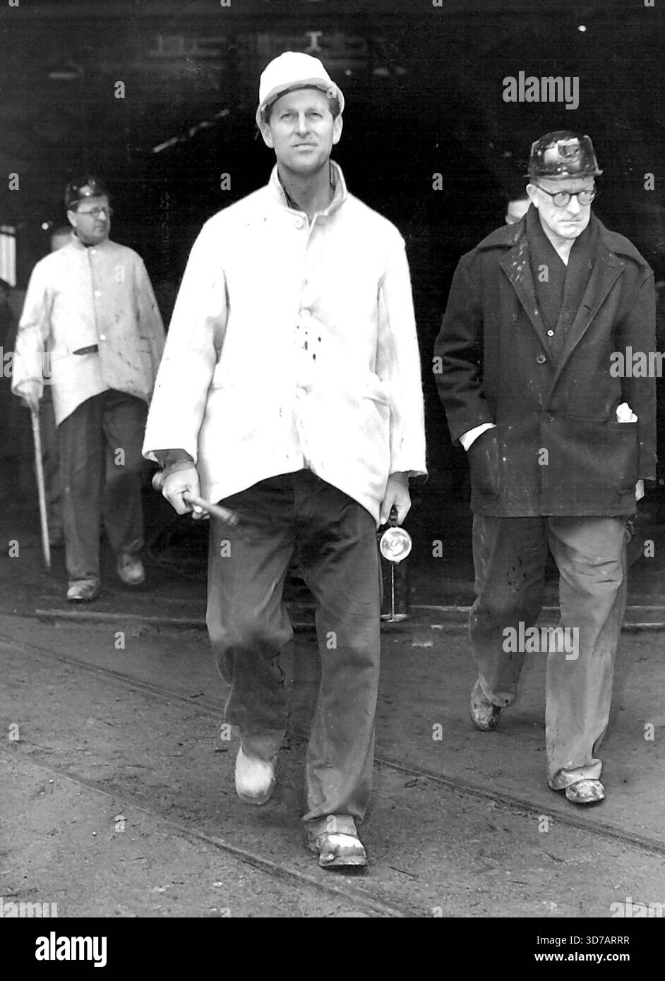 The Royal Miner - portant un casque de mineur blanc et un duffle-coat crème sur une salopette bleu marine, avec de lourdes bottes minières, H.R. H. le duc d'Édimbourg est vu quitter l'ascenseur après être remonté de la fosse à Fernhill Colliery, Rhondda, cet après-midi. Son Altesse Royale le duc d'Édimbourg, qui est au sud du pays de Galles pour présenter la charte de constitution au nouvel arrondissement municipal de Rhondda, a rendu visite aujourd'hui à la mine de charbon Fernhill dans la vallée de Rhondda. Le duc marcha 2½ miles jusqu'au front de charbon et Duke passa une heure et demie dans la fosse, à 900 pieds sous terre. 28 avril 1955. (Photo Banque D'Images