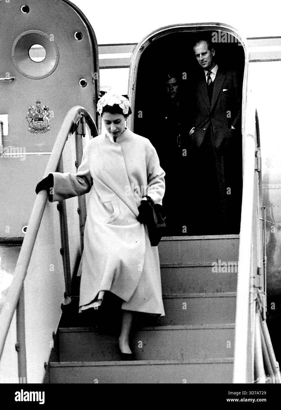 L'adieu de la Reine au duc -- la Reine quitte l'avion après avoir dit au revoir au duc d'Édimbourg (vu dans la porte). Alors que la reine quittait l'avion, la pluie est revenue et elle a fait irruption dans une course pour atteindre sa voiture. Vu au large par la reine, le duc d'Édimbourg a quitté la Royal Air Force Station, Tangmere, Sussex, jusqu'à la nuit (mercredi) dans un avion C.5 de l'Aviation royale canadienne pour Ottawa, où il commencera une tournée de trois semaines au Canada. 28 juillet 1954. Banque D'Images