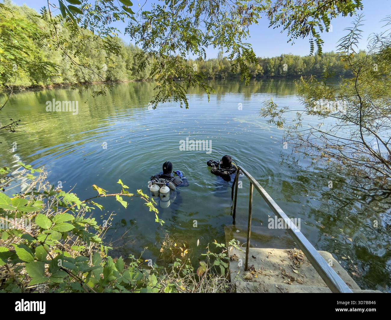 Plongeurs récréatifs avec équipement de plongée les réservoirs de plongée nagent près de la rive sur la surface de l'eau d'un petit lac, en Allemagne Banque D'Images