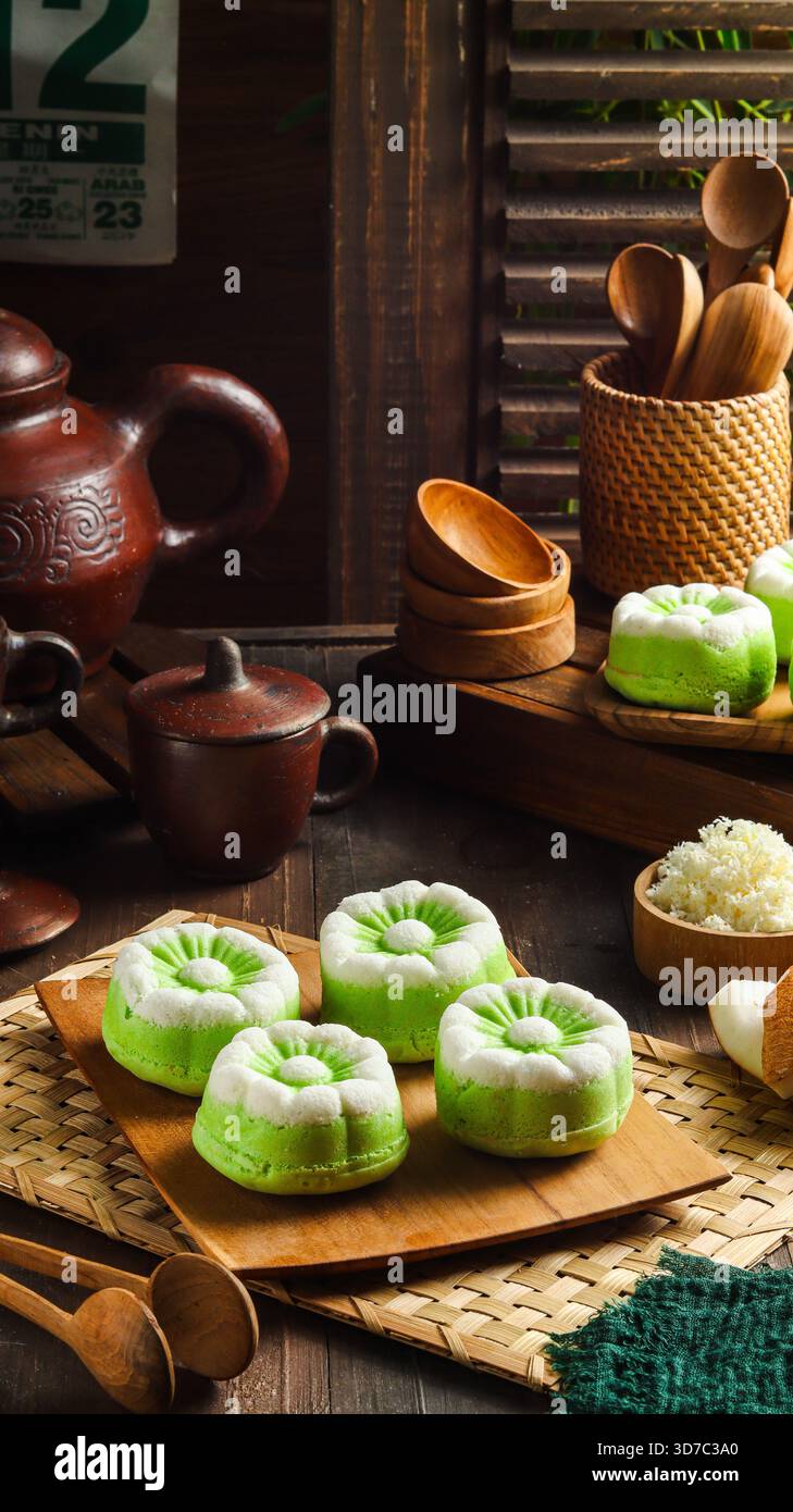 Elégant gâteau Putu Ayu, un gâteau traditionnel indonésien cuit à la vapeur à la saveur de pandan et à la noix de coco râpée, servi sur une assiette en bois Banque D'Images