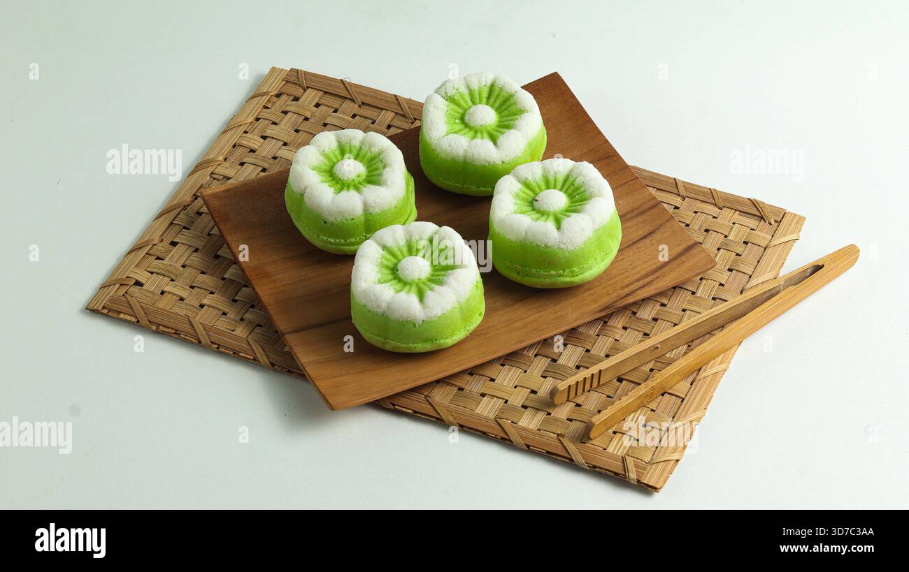 Elégant gâteau Putu Ayu, un gâteau traditionnel indonésien cuit à la vapeur à la saveur de pandan et à la noix de coco râpée, servi sur une assiette en bois Banque D'Images