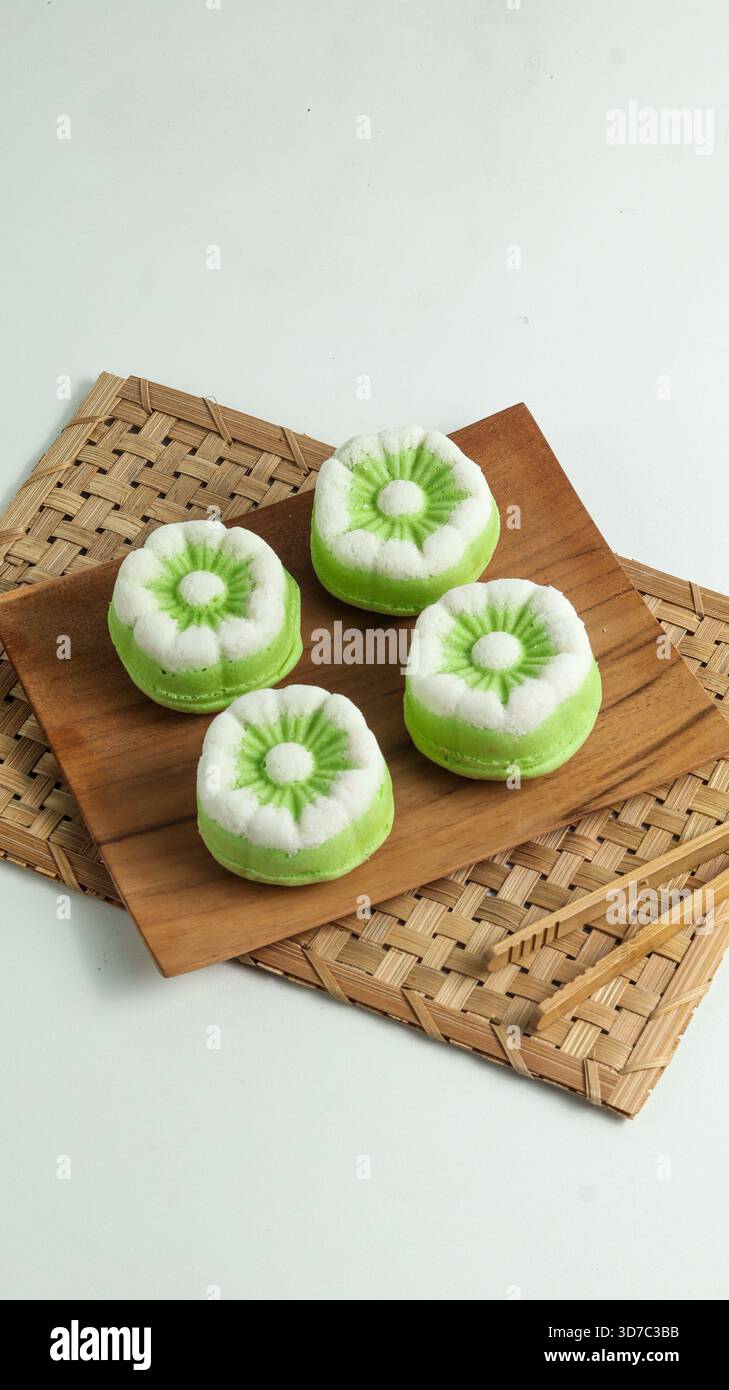 Elégant gâteau Putu Ayu, un gâteau traditionnel indonésien cuit à la vapeur à la saveur de pandan et à la noix de coco râpée, servi sur une assiette en bois Banque D'Images