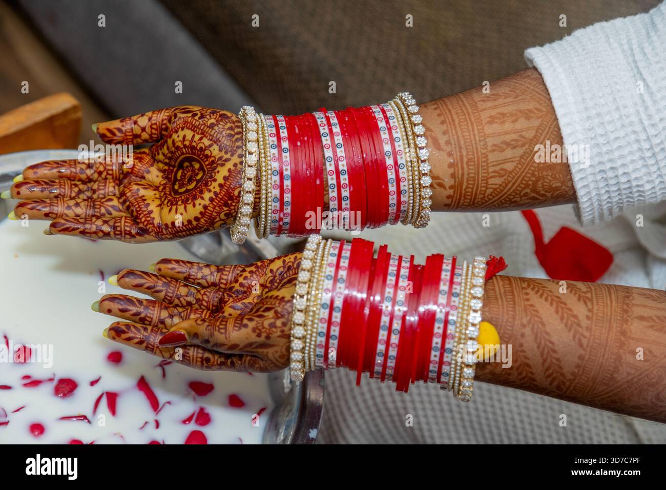 Les mains de la mariée sont ornées de motifs complexes de henné et de bracelets rouges traditionnels, symbolisant l'amour et la prospérité Banque D'Images