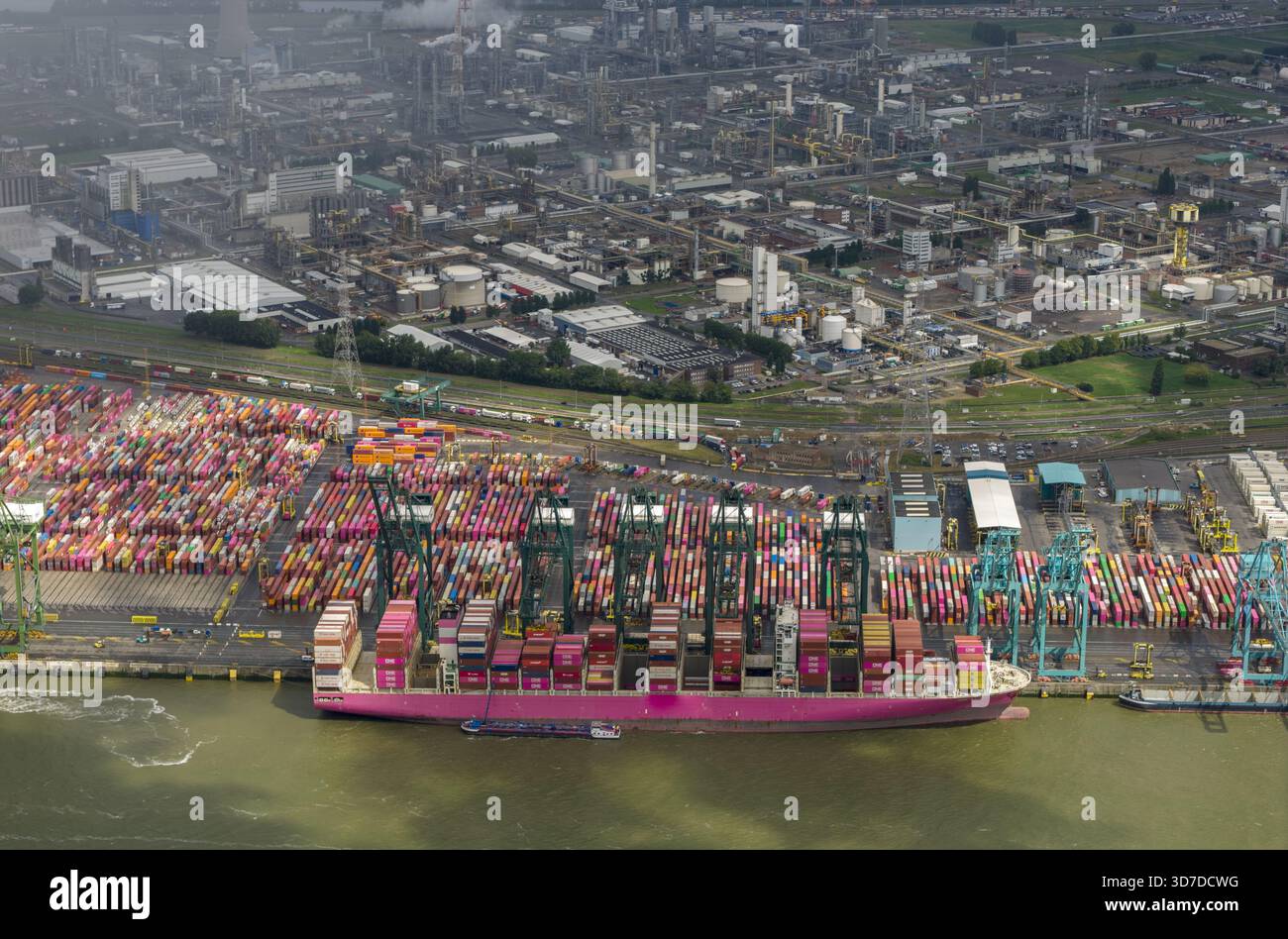 Vue aérienne d'un cargo transportant des conteneurs colorés amarré au port au milieu du complexe industriel tentaculaire, Anvers, Vlaanderen, Belgique. Banque D'Images
