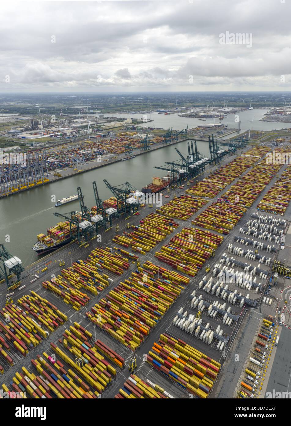 Vue aérienne d'un vaste port rempli de conteneurs colorés empilés haut sous un ciel nuageux, grues qui planent au-dessus des navires, Anvers, Vlaanderen, Belgique. Banque D'Images