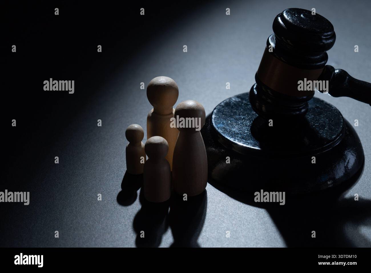 Un marteau en bois à côté d'un groupe de quatre poupées en bois. Droit de la famille, justice juridique, garde des enfants, politique sociale et concept de protection de la famille. Banque D'Images