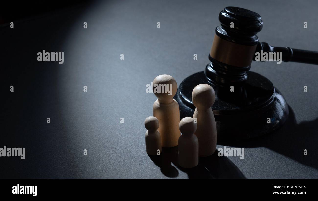 Un marteau en bois à côté d'un groupe de quatre poupées en bois. Droit de la famille, justice juridique, garde des enfants, politique sociale et concept de protection de la famille. Banque D'Images
