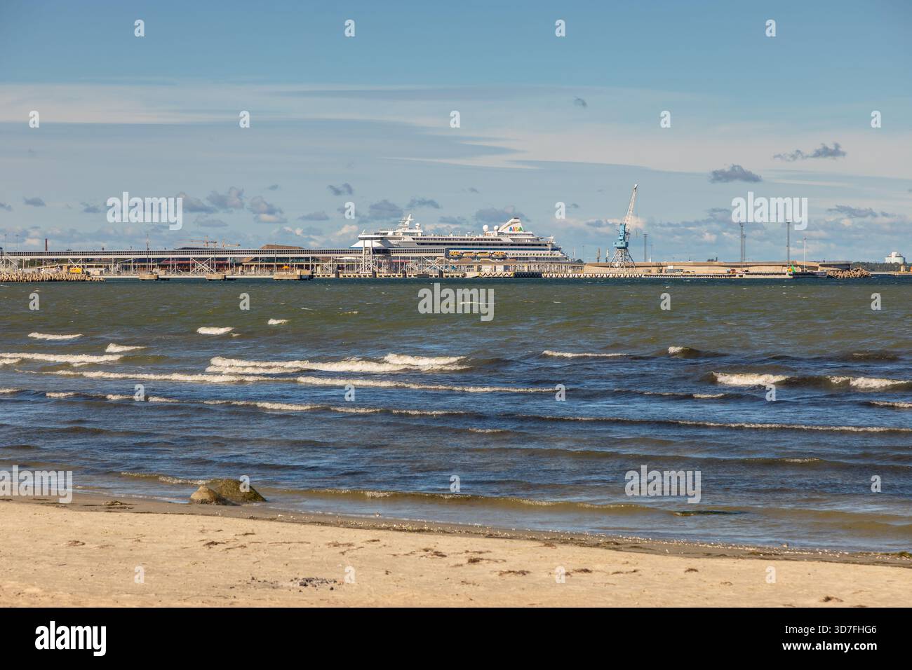 Tallinn, Estonie – 02 septembre 2021 : les vagues atteignent la plage de sable avec un bateau de croisière amarré au port en arrière-plan. Banque D'Images