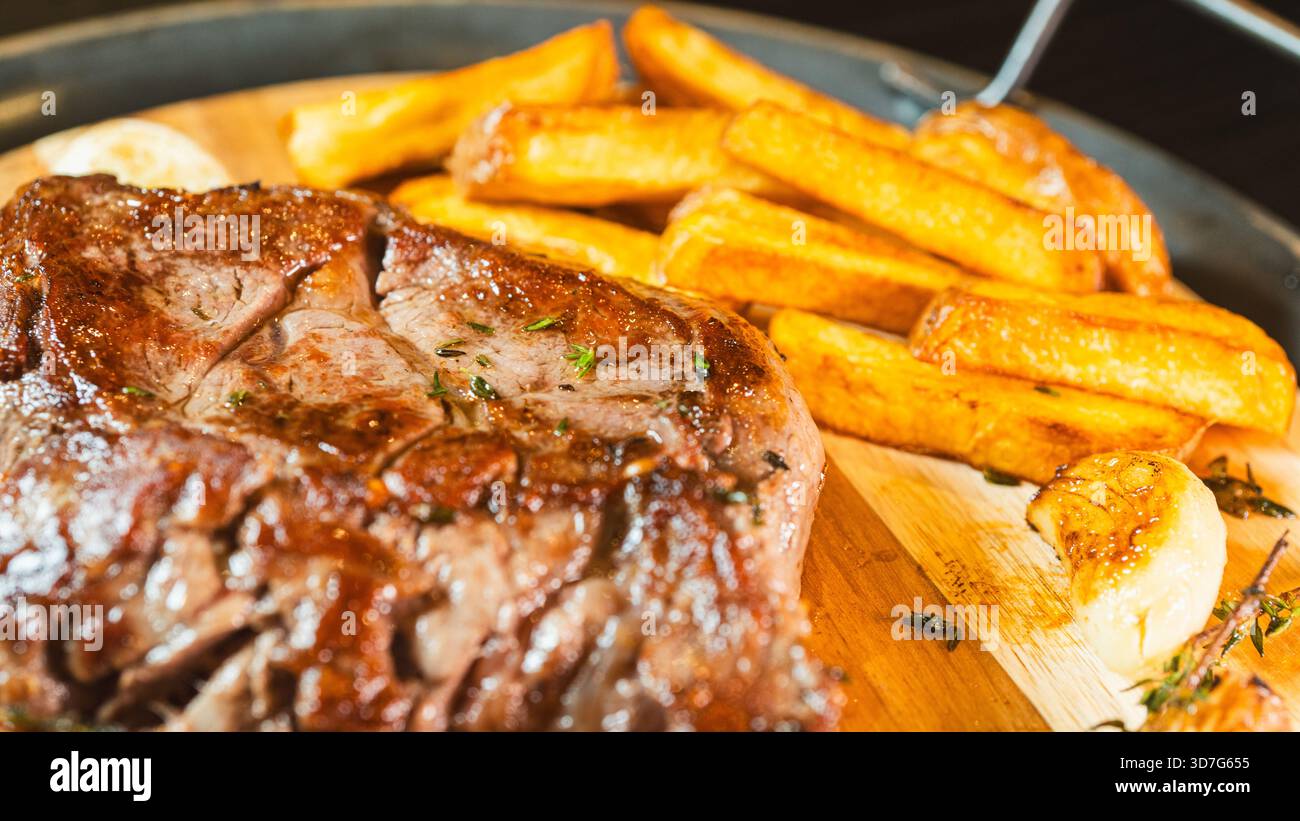 Gros plan de steak de ribeye juteux sur une planche de bois avec frites maison, tomates cerises et thym frais. Présentation gastronomique, parfaite pour le contenu alimentaire. Banque D'Images