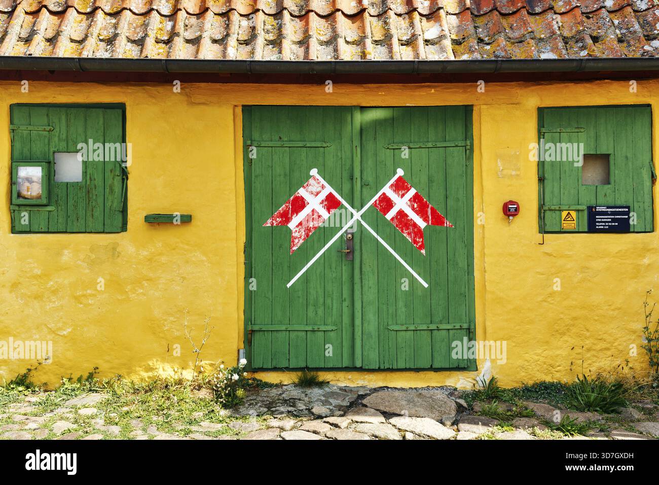 Christianso Skole, la plus petite école du Danemark, détail de façade, jaune et vert caractéristique, drapeaux danois croisés, Dannebrog, Christianso, Christ Banque D'Images