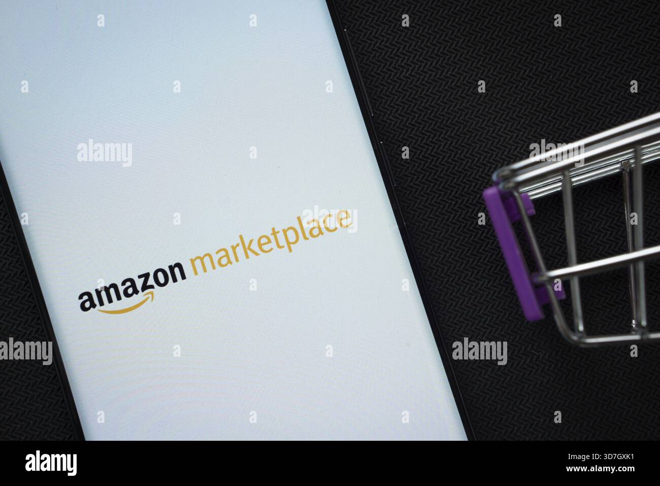 Dhaka, Bangladesh- 21 novembre 2025 : un smartphone affichant le logo amazon Marketplace à côté d'un panier miniature sur un fond Banque D'Images