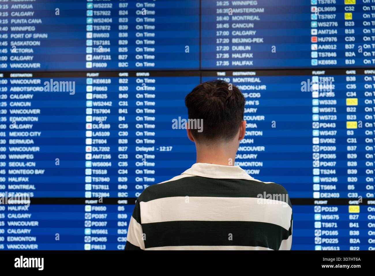 Le voyageur vérifie le panneau d'information de vol au terminal de l'aéroport. Toronto, ONTARIO Banque D'Images