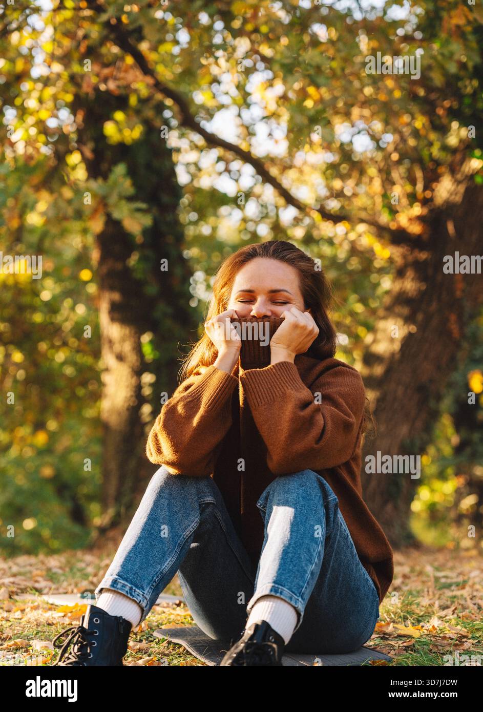 Jeune femme se relaxant dans le parc de la ville d'automne portant un pull confortable Banque D'Images