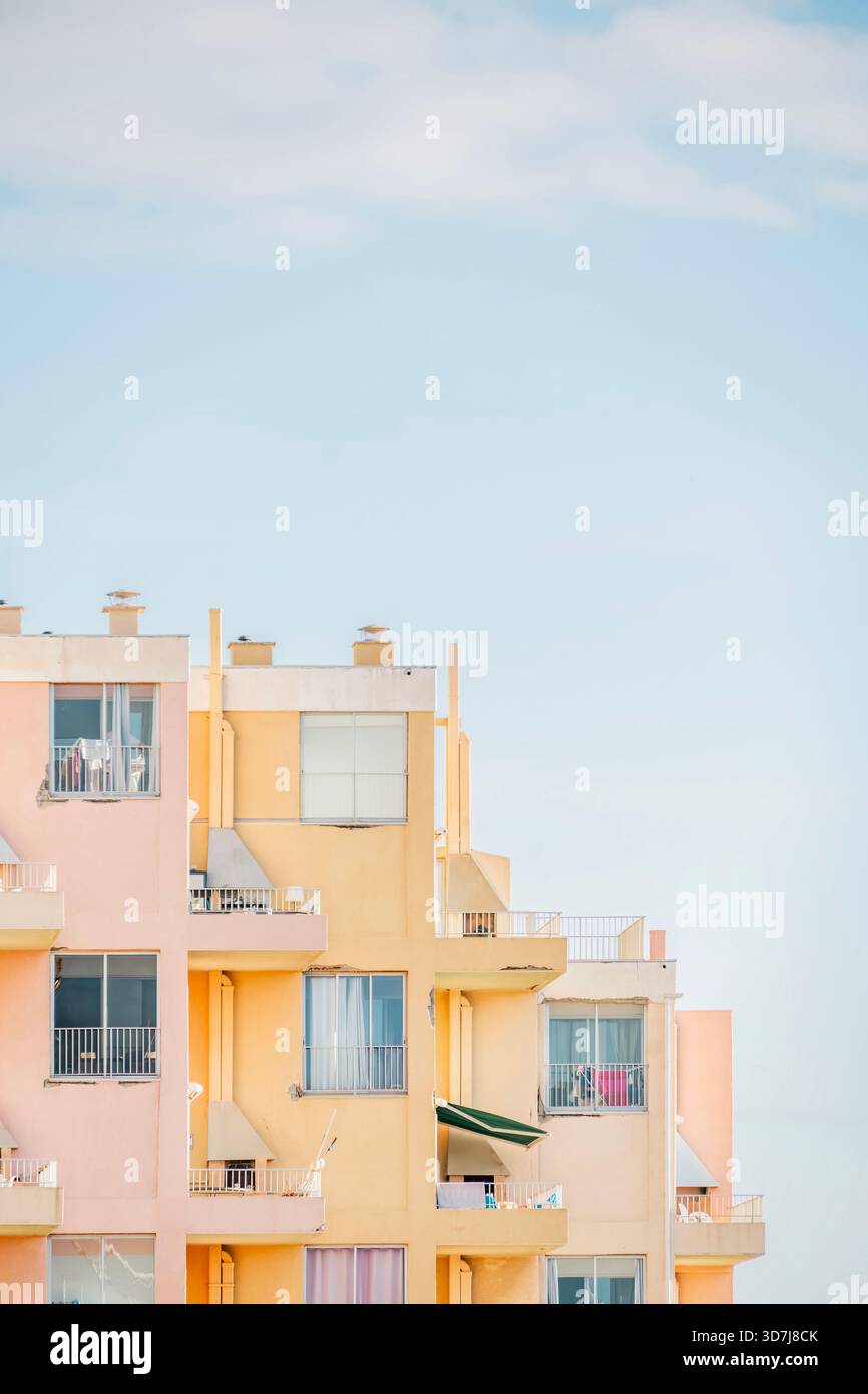 Gros plan vertical d'une façade d'immeuble à gradins en rose pastel doux et jaune Banque D'Images