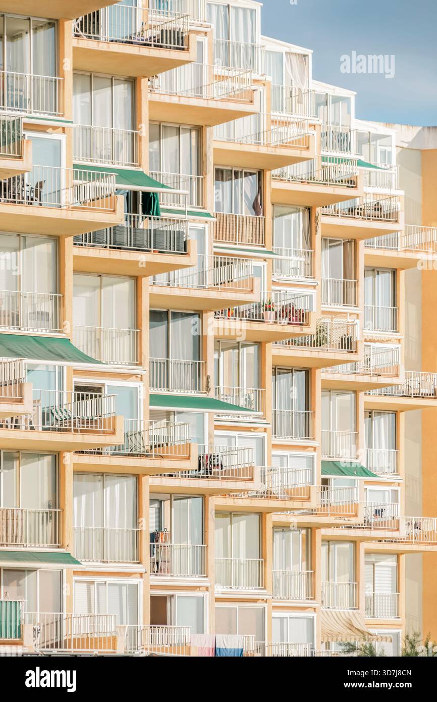 Balcons et fenêtres densément emballés d'un immeuble à plusieurs étages, formant un motif géométrique complexe avec des couleurs orange et blanc Banque D'Images