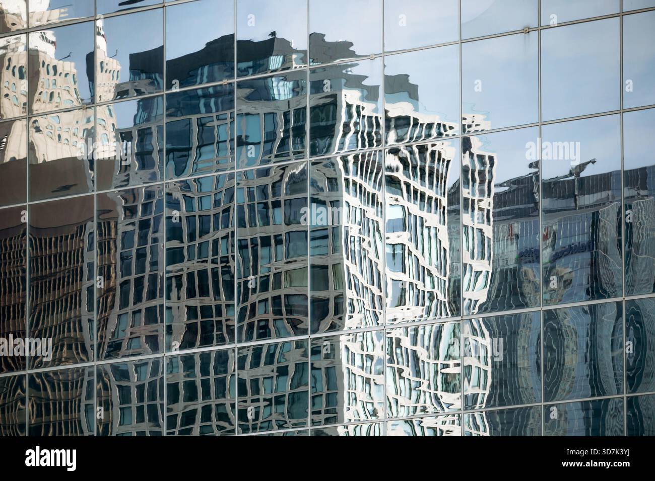 Reflet des gratte-ciel du centre-ville de Montréal déformé dans la façade vitrée d’un bâtiment moderne, créant un motif urbain abstrait Banque D'Images
