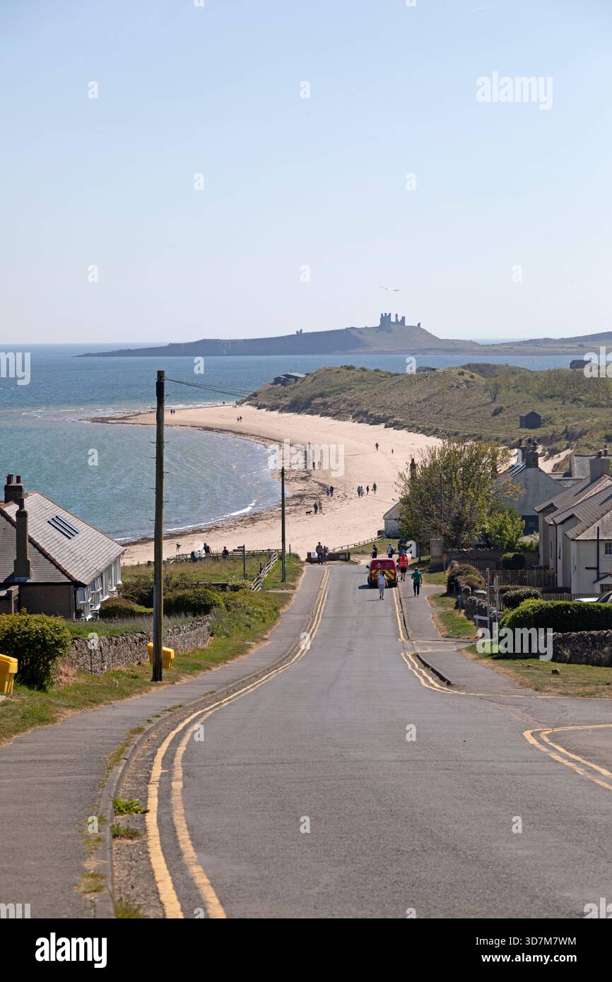 La route vers Embleton Beach dans le Northumberland, Angleterre. Les ruines du château de Dunstanburgh peuvent être vues au loin. Banque D'Images
