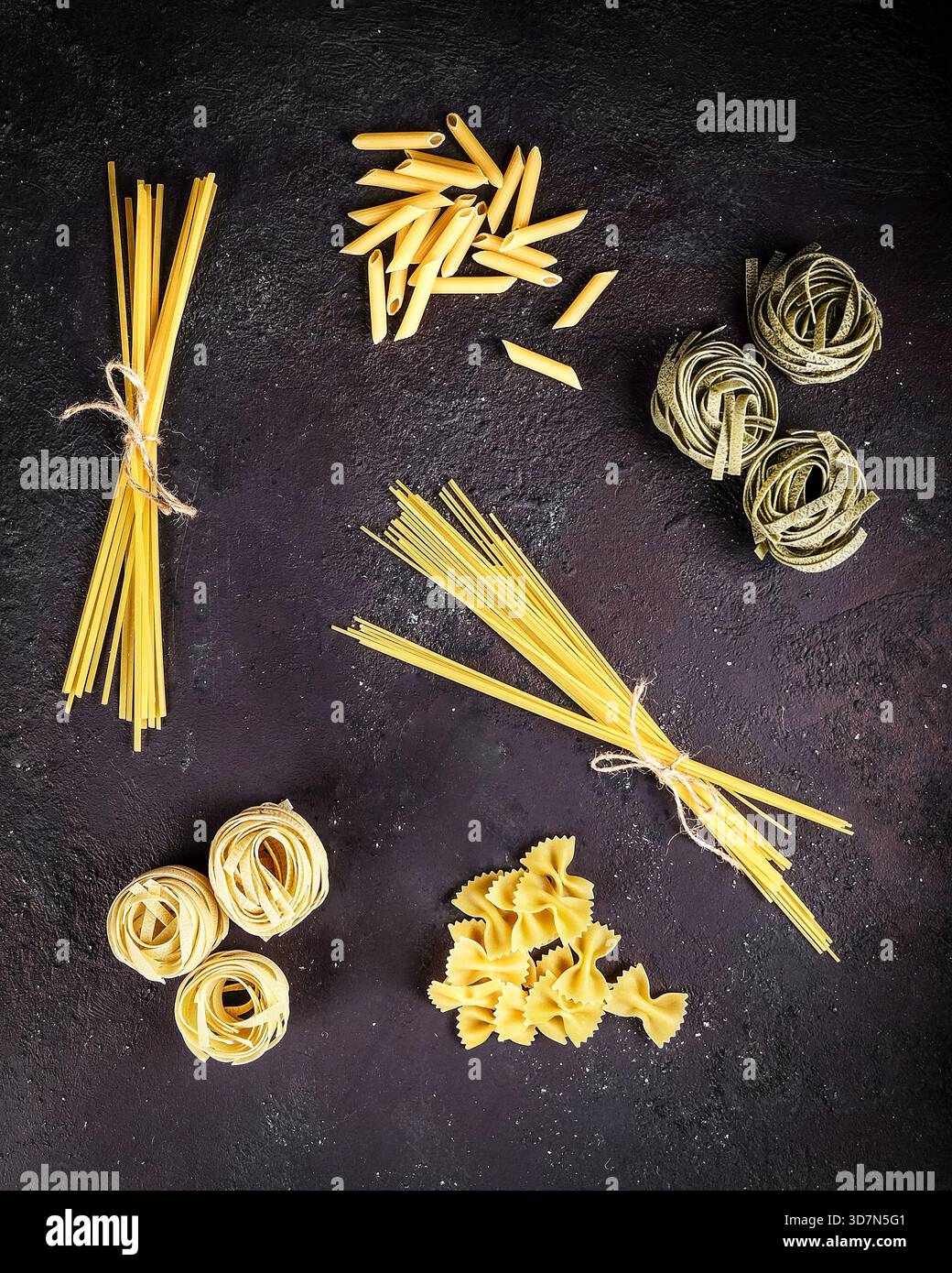Différents types de pâtes non cuites disposées sur fond d'ardoise rustique Banque D'Images