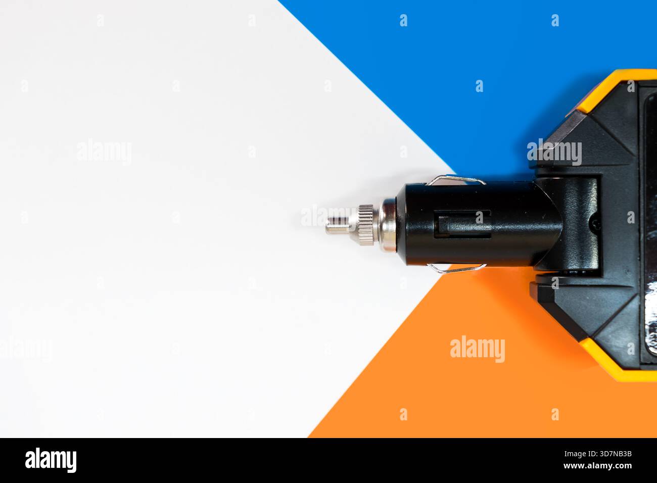 Grand adaptateur électrique pour recharger des appareils à travers une prise allume-cigare de voiture, sur fond coloré. Banque D'Images