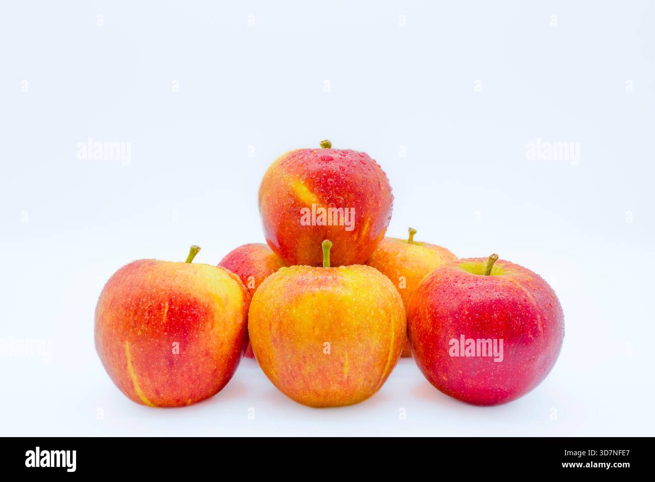 Six pommes rouges en forme de pyramide recouvertes de gouttelettes d'eau. Banque D'Images