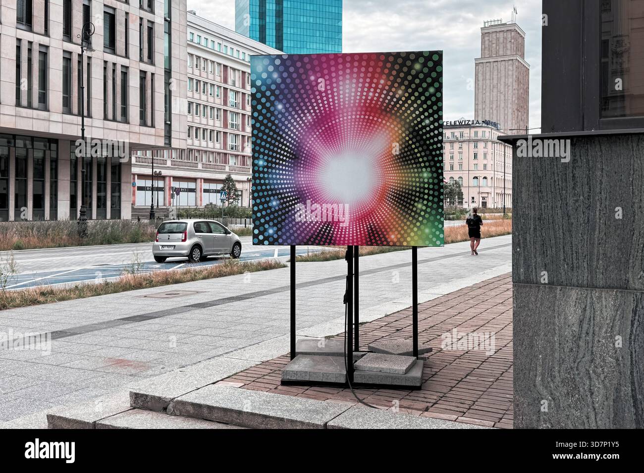 Panneau d'art abstrait coloré exposé à l'extérieur dans un paysage urbain moderne, créant un contraste visuel saisissant avec les bâtiments environnants. Banque D'Images