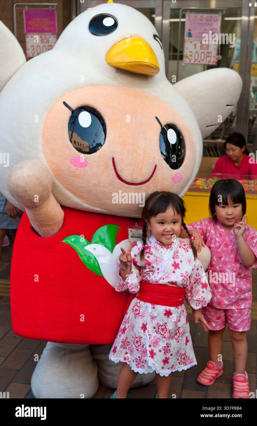 Les enfants interagissent avec Heiwado 'Hatoppi' (はとっぴー ?) personnage de mascotte japonais yuru-kyara pour le grand magasin Shiga vu lors d'un événement à Hikone, au Japon. Banque D'Images