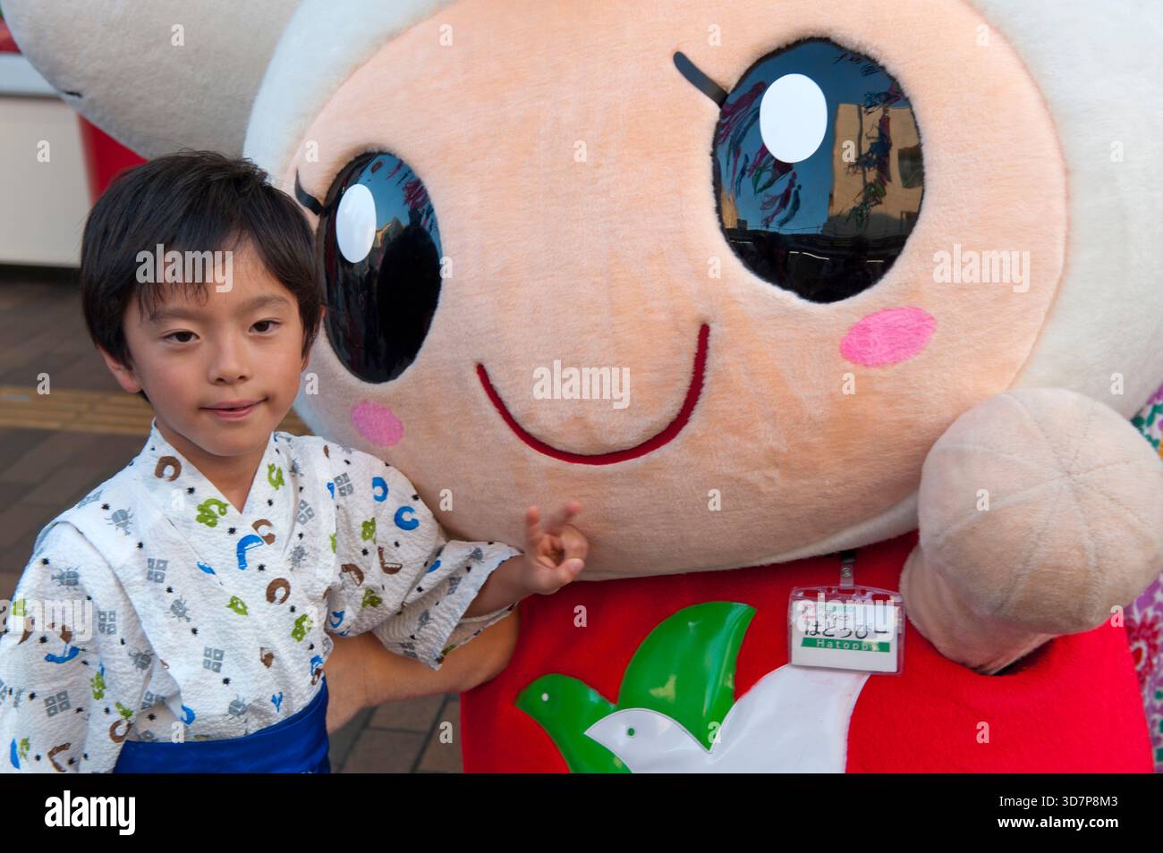 Les enfants interagissent avec Heiwado 'Hatoppi' (はとっぴー ?) personnage de mascotte japonais yuru-kyara pour le grand magasin Shiga vu lors d'un événement à Hikone, au Japon. Banque D'Images