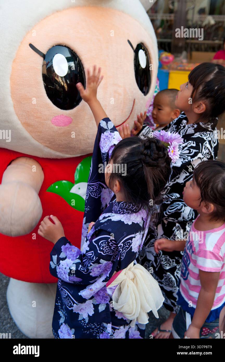 Les enfants interagissent avec Heiwado 'Hatoppi' (はとっぴー ?) personnage de mascotte japonais yuru-kyara pour le grand magasin Shiga vu lors d'un événement à Hikone, au Japon. Banque D'Images