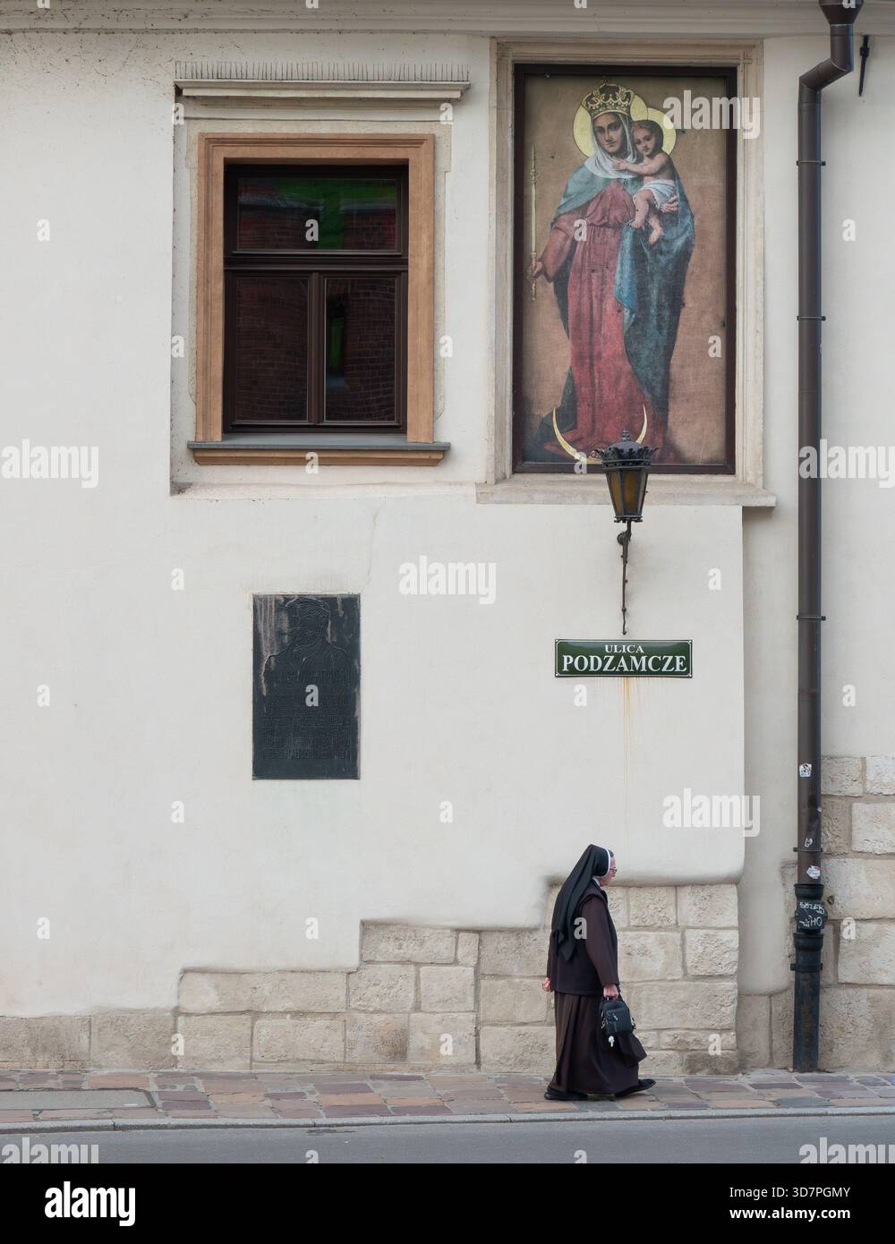 Cracovie Pologne. Célèbre pour sa riche histoire et son architecture, le vieux centre-ville de Cracovie est classé au patrimoine mondial de l'UNESCO. Une religieuse marche le long d'une rue. Banque D'Images