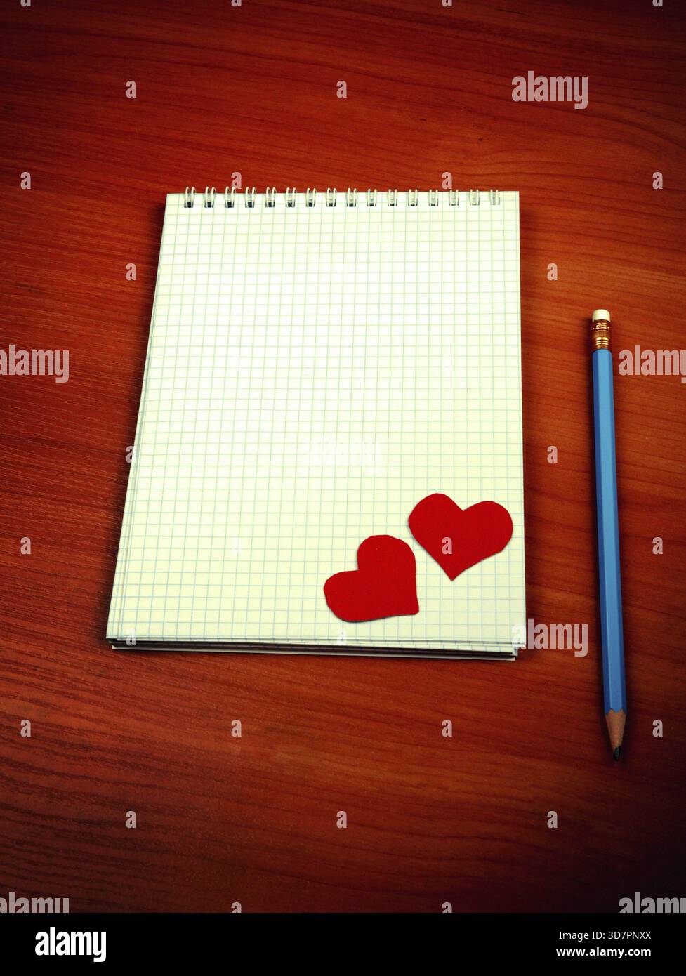 Photo teintée d'un bloc d'écriture vierge avec formes de coeur et crayon sur la table Banque D'Images