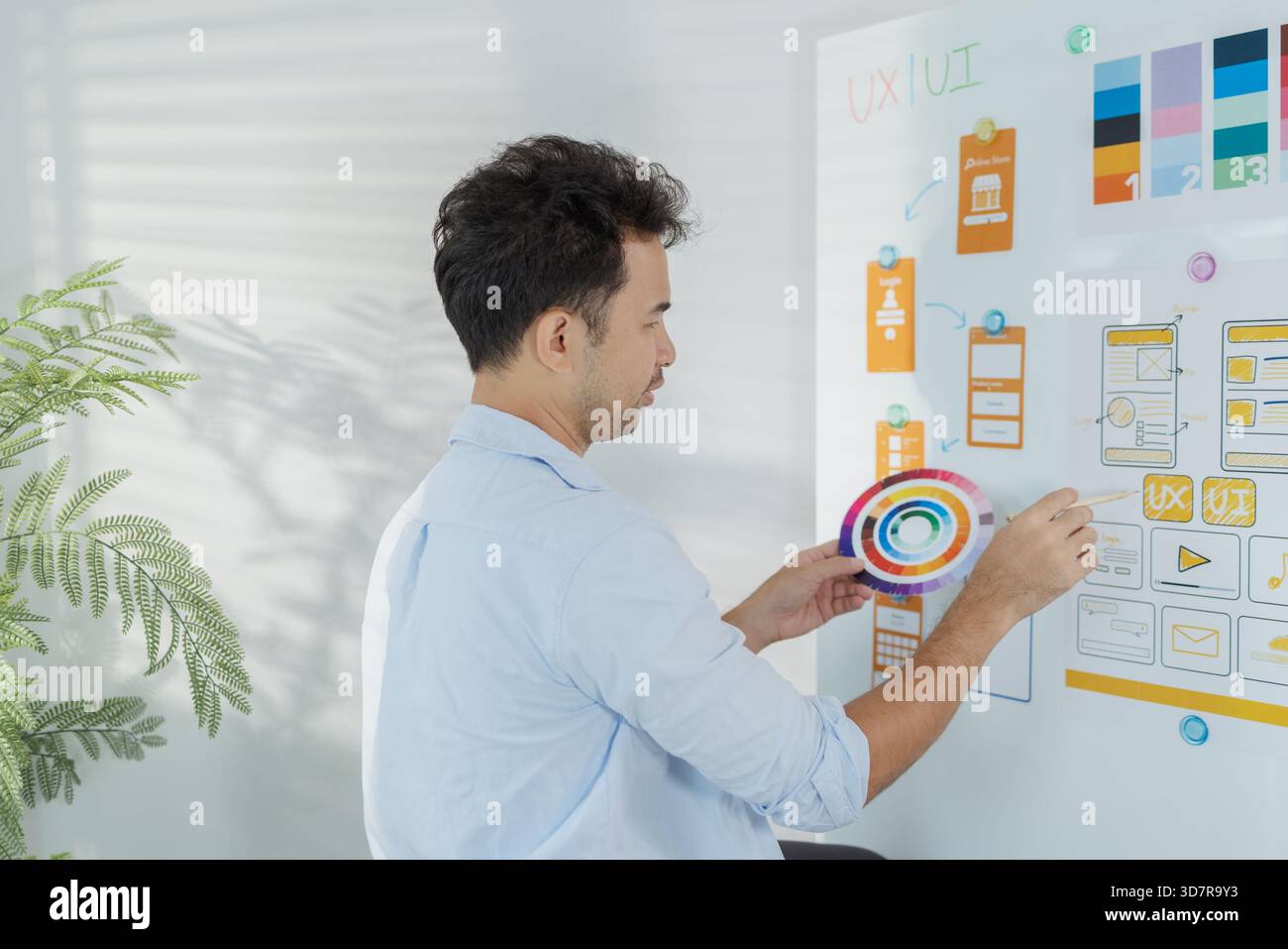 Un concepteur créatif travaille sur la planification de l'interface utilisateur UX, la révision des wireframes et l'ajustement des schémas de couleurs pour un projet d'application mobile, montrant Focus an Banque D'Images