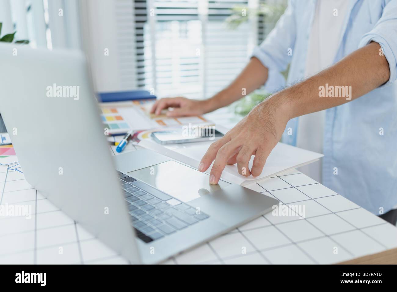 Un concepteur créatif travaille sur la planification UX/UI, analysant des croquis et des prototypes sur un tableau blanc tout en utilisant un ordinateur portable. Le processus montre la pensée de conception Banque D'Images