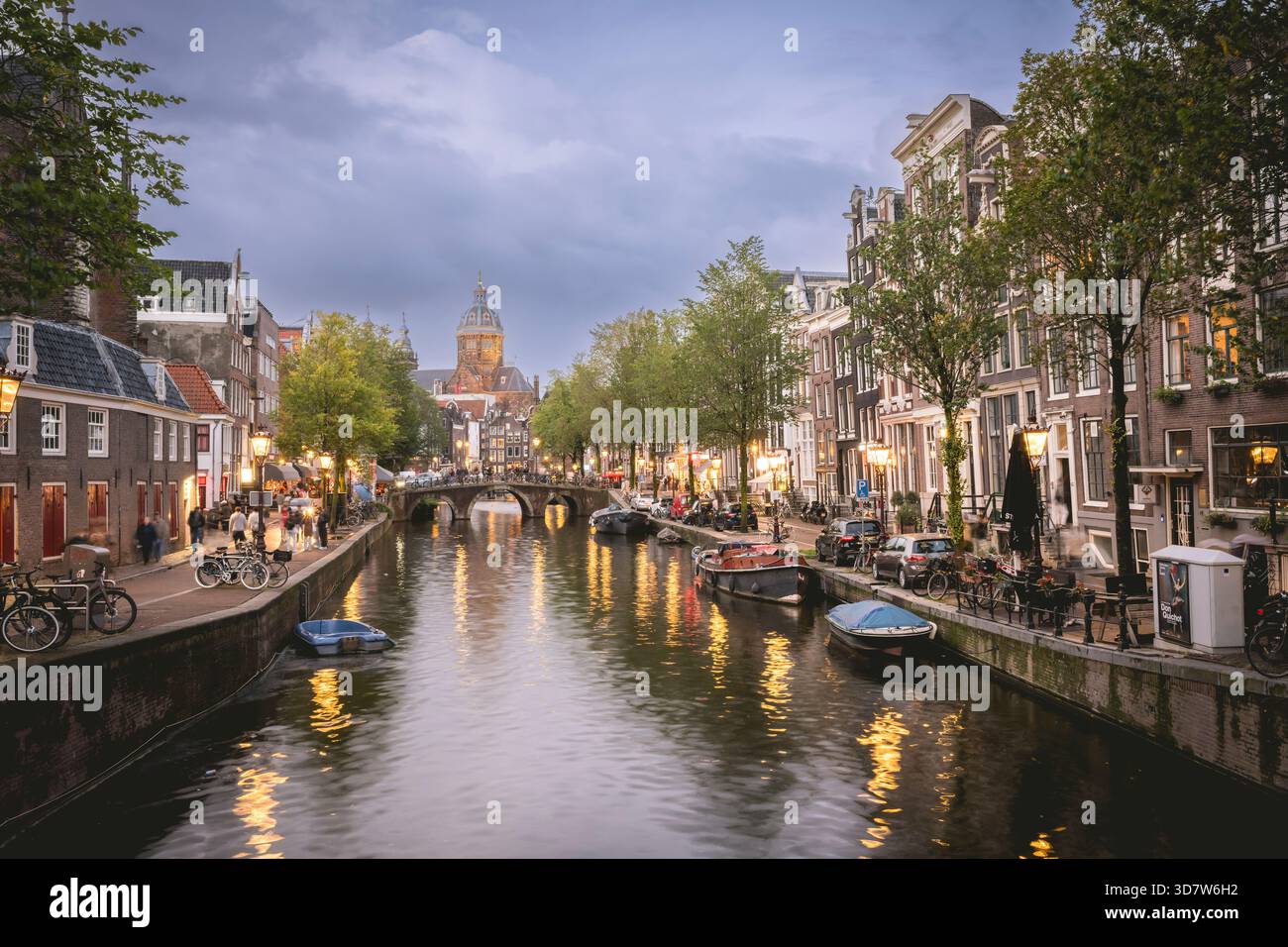Charmante scène de canal au crépuscule avec des bâtiments historiques et des lampadaires reflétant dans l'eau. Amsterdam,. Pays-Bas Banque D'Images