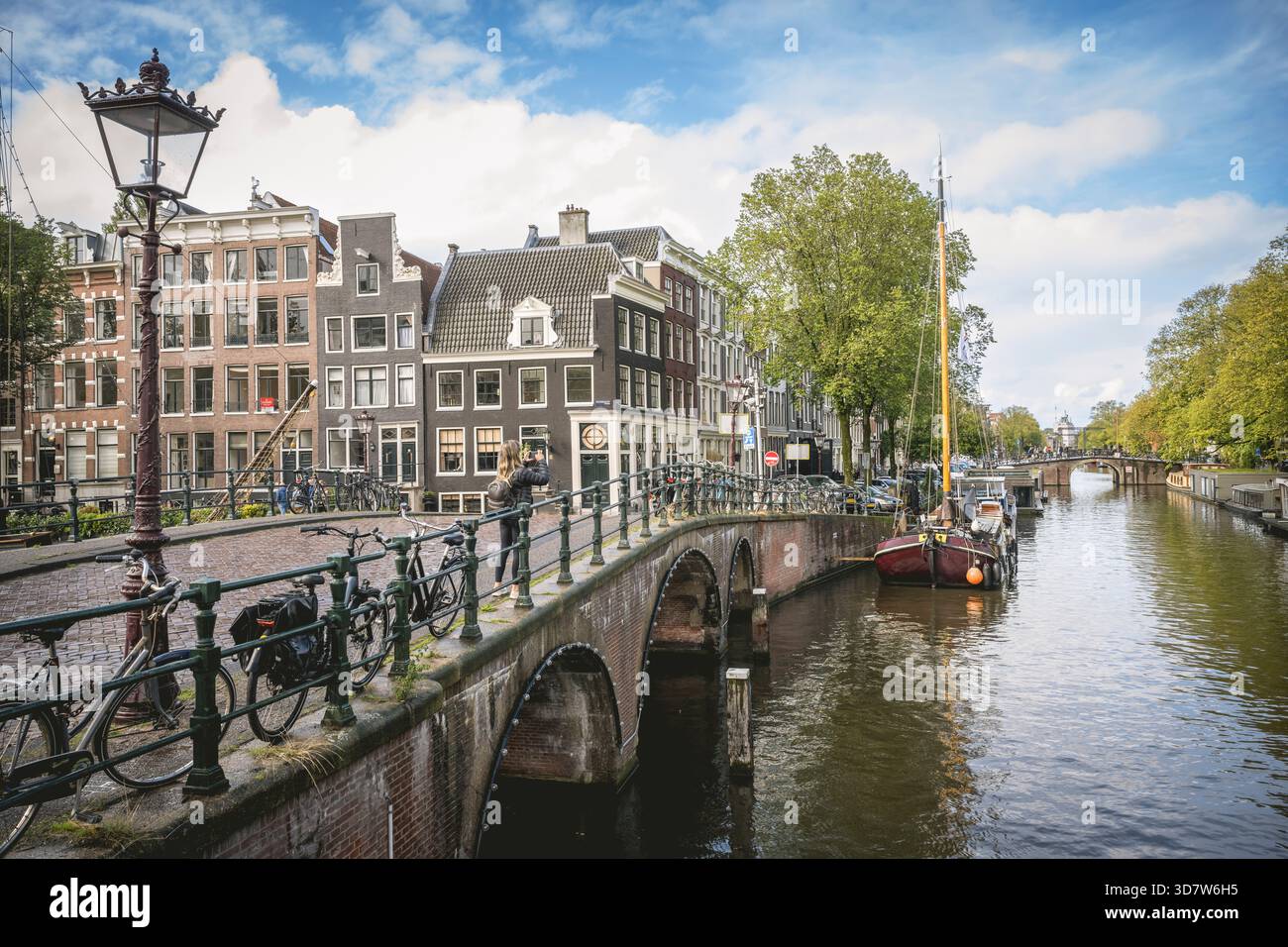 Une vue panoramique sur un canal d'Amsterdam avec un pont et des maisons traditionnelles sous un ciel bleu. Amsterdam,. Pays-Bas Banque D'Images