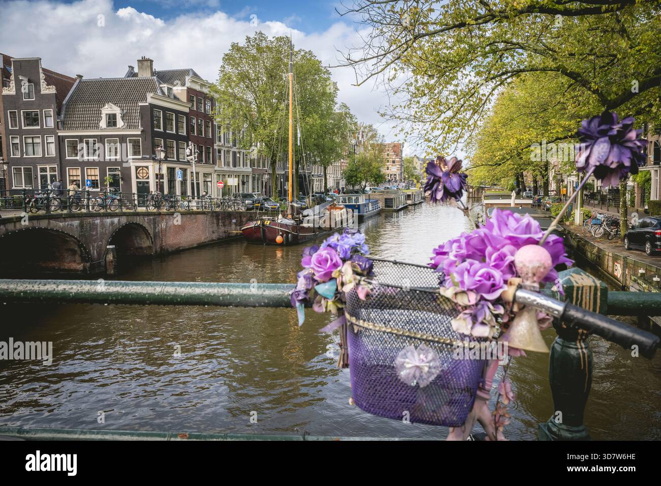 Un canal pittoresque dans une ville avec des bâtiments historiques et un panier à vélos décoré de fleurs. Amsterdam,. Pays-Bas Banque D'Images