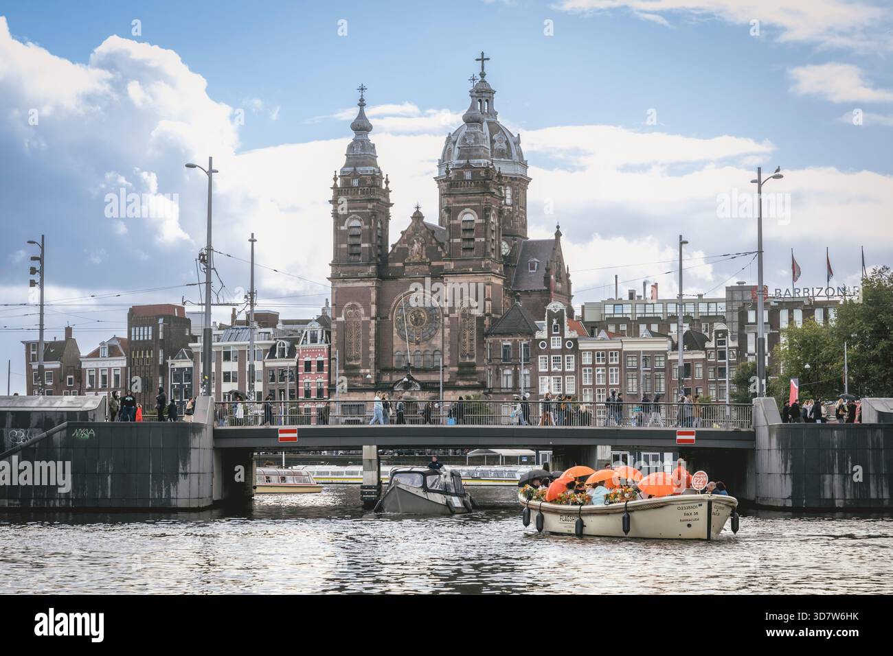 Bateau avec des fleurs sur un canal avec église historique et ciel nuageux en arrière-plan. Amsterdam,. Pays-Bas Banque D'Images