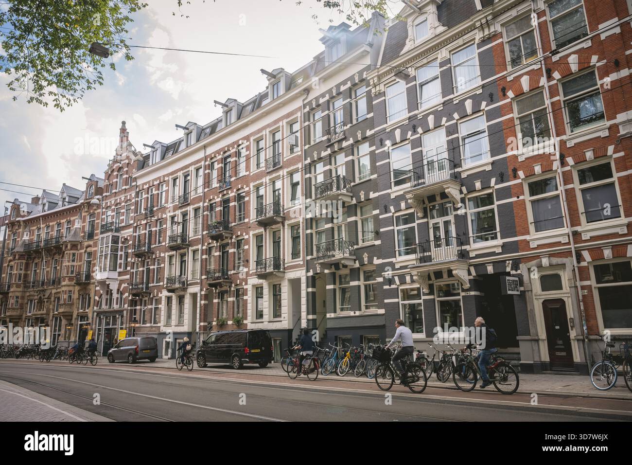 Rue européenne historique avec des vélos, bordée de maisons de ville en briques sous un ciel partiellement nuageux. Amsterdam,. Pays-Bas Banque D'Images