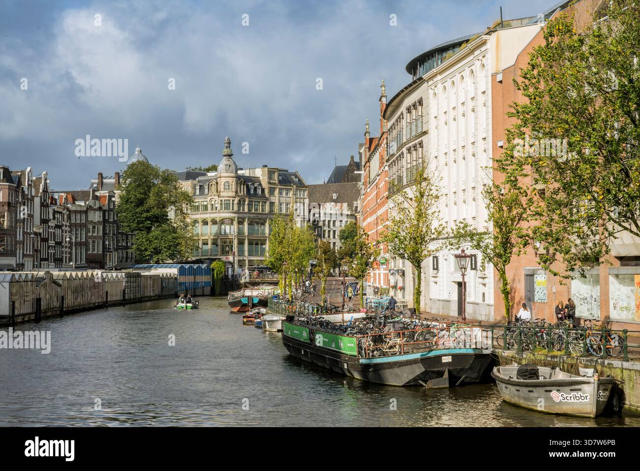 Vue panoramique sur un canal bordé de bateaux et de bâtiments historiques sous un ciel nuageux. Amsterdam,. Pays-Bas Banque D'Images