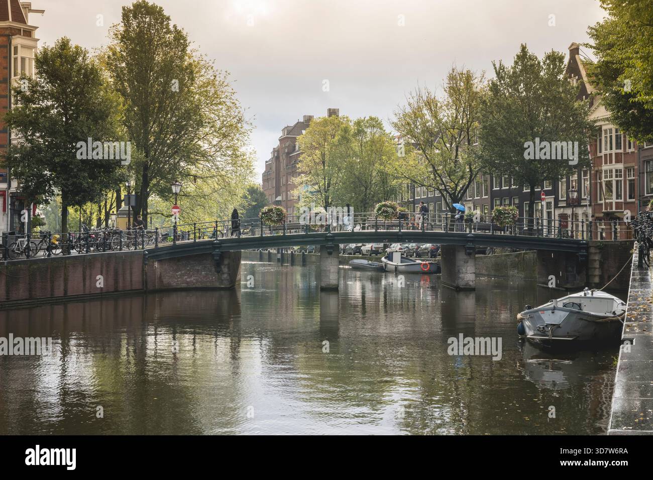 Vue panoramique sur un canal dans une ville avec un pont et des arbres verdoyants. Amsterdam,. Pays-Bas Banque D'Images
