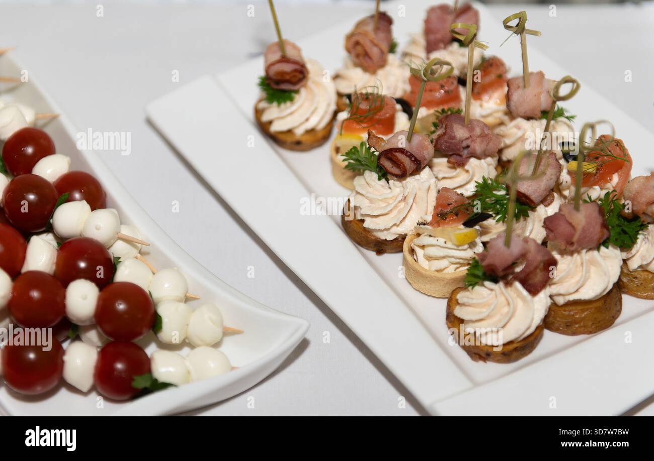 Canapés de mariage avec fromage, bacon et tomates disposés sur des assiettes pour la célébration en Lettonie. Banque D'Images