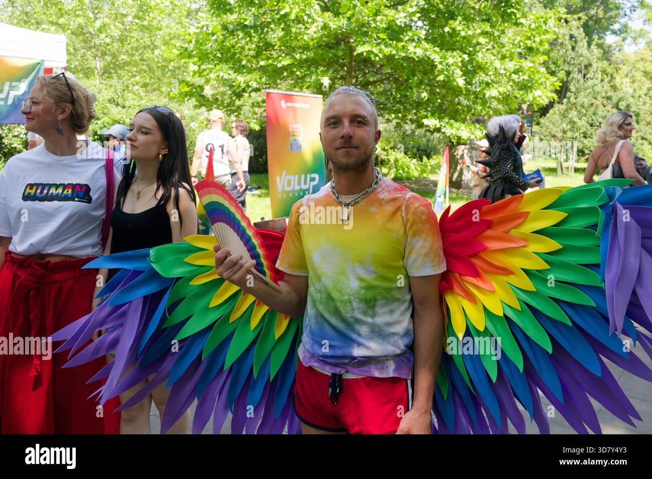 Un participant portant des ailes arc-en-ciel et une chemise teintée assiste à la Warsaw Pride (Parada Równości), célébrant la diversité avec des tenues colorées. Banque D'Images