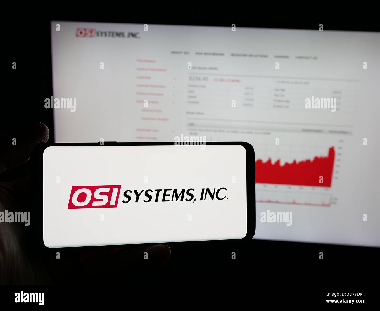 Stuttgart, Allemagne - 11-18-2025 : personne tenant un smartphone avec le logo de la société de sécurité américaine OSI Systems Inc sur l'écran devant le site Web. Banque D'Images